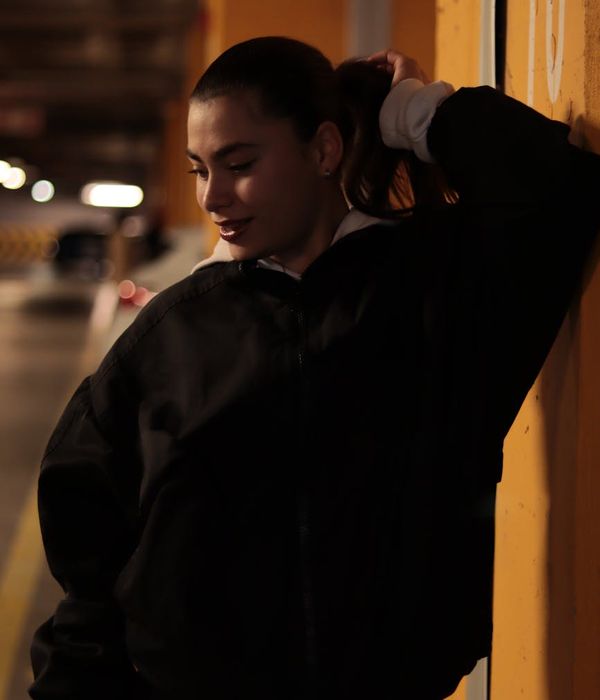 Woman in a calm yoga pose against a dark background with a yellow accent.